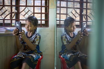 A girl is playing with a mobile phone.